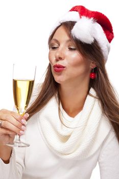 Playful woman wearing a festive red Santa hat and holding a flute of champagne celebrating Christmas blowing a kiss across the palm of her hand with a mischievous smile, on white