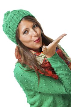 Romantic pretty young woman in a knitted green winter outfit blowing a kiss across the palm of her hand to her sweetheart or while flirting, isolated on white