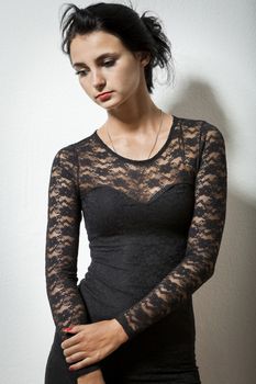 Portrait of Gorgeous Young Woman in Elegant Black Dress Carrying her Jacket on Gray Wall Background.