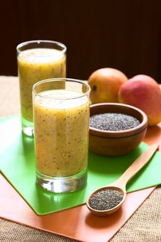 Chia seed (lat. Salvia hispanica) and mango juice photographed with natural light. Chia seeds are considered a superfood containing proteins, omega fats, minerals and antioxidants (Selective Focus, Focus on the front of the juice and the seeds on the spoon)