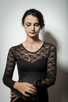 Portrait of Gorgeous Young Woman in Elegant Black Dress Carrying her Jacket on Gray Wall Background.