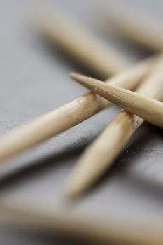 Pile of wooden toothpicks scattered randomly on a grey background for cleaning between the teeth after a meal in a personal hygiene concept