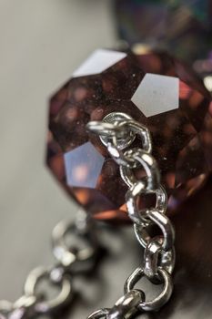 Close up of three attractive shiny purple beads attached by silver chains on an item of jewellery in a fashion and handicraft concept