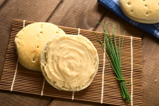 Overhead shot of cream cheese spread on bun with a bundle of chives on the side, photographed with natural light 