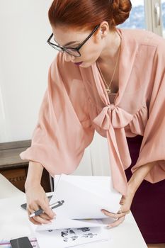 Serious Young Office Woman Writing a Document on Top of her Desk While in Standing Position.