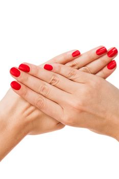 Woman with beautiful manicured red fingernails gracefully crossing her hands to display them to the viewer on a white background in a fashion, glamour and beauty concept