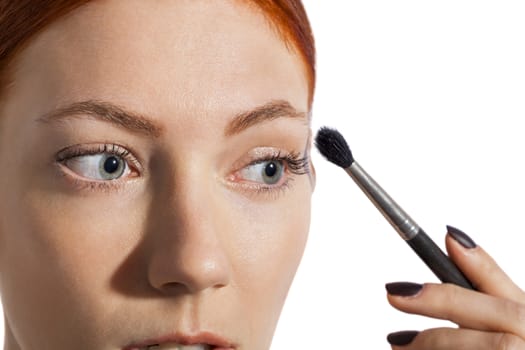 Close up Pretty Woman Applying Eye Shadow Makeup Using Brush on White Background.