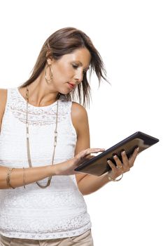 Attractive young business woman standing chatting on a mobile while simultaneously reading a tablet computer with a smile, isolated on white