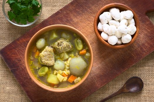 Overhead shot of traditional Bolivian soup called Chairo de Tunta (tunta is a freeze-dried potato typical in the Andean regions) made of tunta, beef, broad beans, peas and carrots, uncooked tunta on the right, photographed with natural light