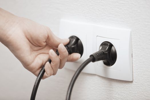 Woman pluging cable to the electric outlet