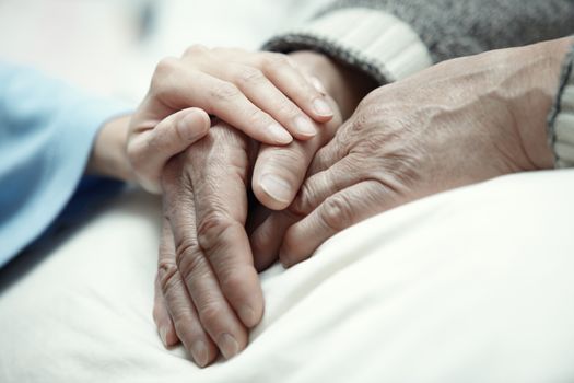 Hand of woman touching senior man in clinic