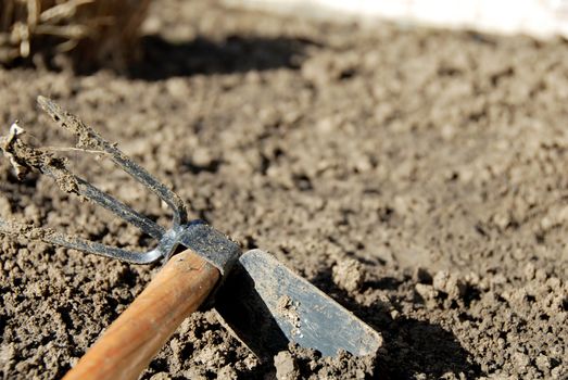 one dirty gardening hand tool - hoe in dirt closeup