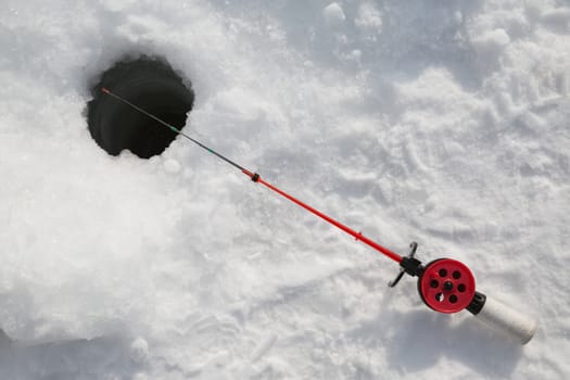 Winter fishing rod in the hole in the snow
