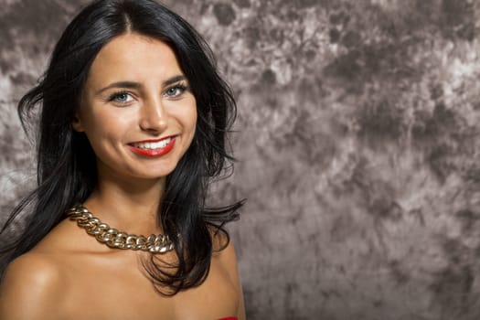 Close up Pretty Young Woman with long Black Hair, Wearing Red. Looking at Right Frame. Captured with Abstract Brown Background.