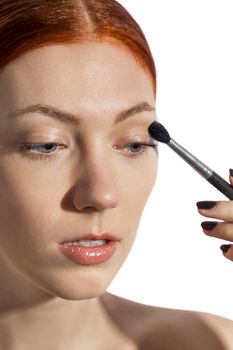 Close up Pretty Woman Applying Eye Shadow Makeup Using Brush on White Background.