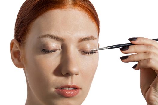 Close up Pretty Woman Applying Eye Shadow Makeup Using Brush on White Background.