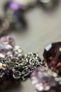 Close up of three attractive shiny purple beads attached by silver chains on an item of jewellery in a fashion and handicraft concept