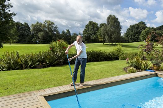 Full Length of Man Cleaning Swimming Pool Using Telescopic Pole