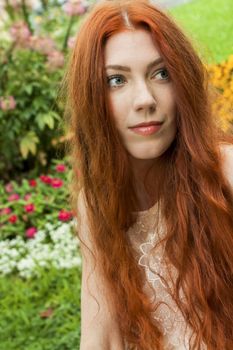 Close up Young Woman with long red Hair Relaxing at the Garden While Looking Afar