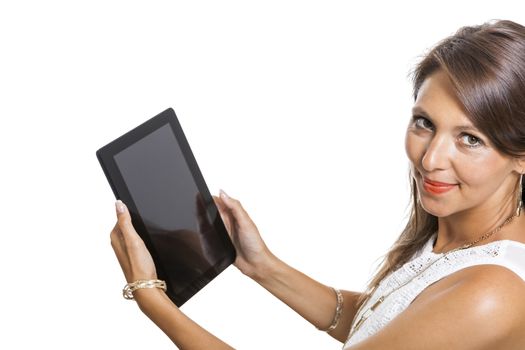 Attractive young business woman standing chatting on a mobile while simultaneously reading a tablet computer with a smile, isolated on white