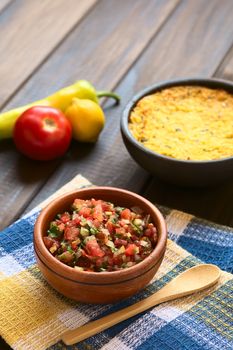 Traditional Chilean Pebre sauce made of tomato, onion, aji verde (small green hot pepper), lemon juice and coriander leaves served for barbecue and traditional dishes, photographed on wood with natural light (Selective Focus, Focus in the middle of the pebre)