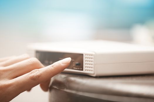 Human hand turning on wireless modem. Close-up horizontal photo