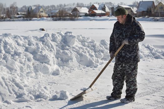 A man in camouflage clothing removes snow shovel