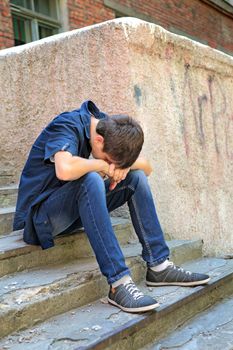 Sad Young Man on the landing Steps of the Old House