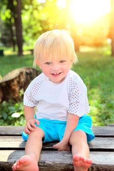 Cheerful Child on the Bench at the Summer Park