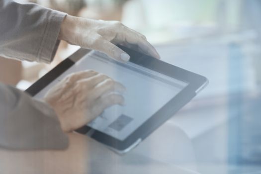 Hands of woman using digital tablet at home behind the window