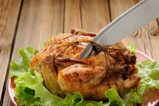 Bondage shibari roasted chicken on wooden background, cutting cord closeup  horizontal