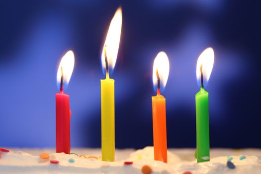 Four lit birthday candles close up, shallow dof
