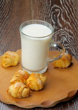 Arrangement of Croissant Cookies with Jam  and Glass Cup of Milk on Wooden Plate closeup on Rustic Wooden background