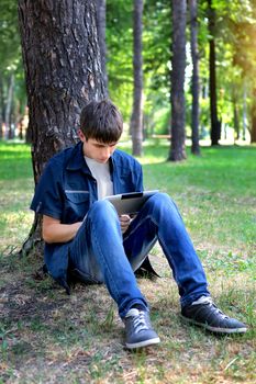 Teenager with Tablet Computer under the Tree in the Summer Park
