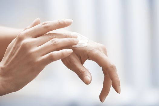 Woman applying moisturizing cream on hands