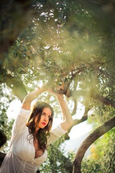 Attractive, young brunette on the beach, amid olive trees, looking both sensual and natural