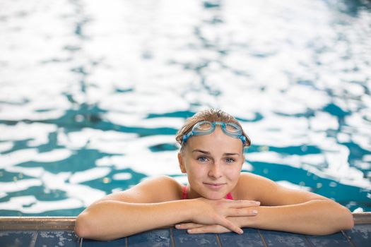 Female swimmer in an indoor swimming pool - looking at the camera, looking content after a good swim (shallow DOF)