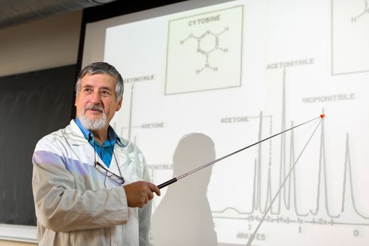 Senior chemistry professor giving a lecture in front of classroom full of students (shallow DOF; color toned image)