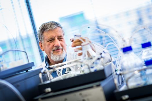 Senior male researcher carrying out scientific research in a lab (shallow DOF; color toned image)