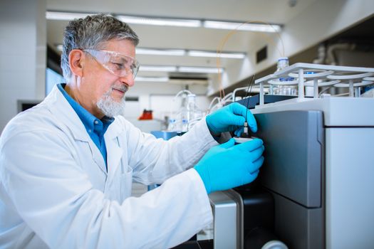 Senior male researcher carrying out scientific research in a lab (shallow DOF; color toned image)