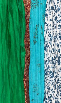 Fabrics vertical. Assortment of fabrics in organic theme - green silk, red indian wool, turquoise gauzy cotton and white cotton with marine blue floral.