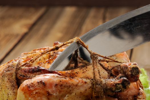 Bondage shibari roasted chicken on wooden background, cutting cord closeup  horizontal