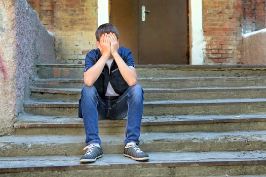 Sad Young Man on the landing Steps of the Old House