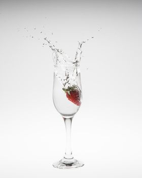 Strawberry falls deeply under water with a splash on white background