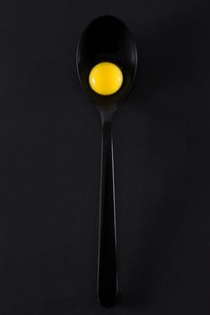 Quail eggs in spoon on black background