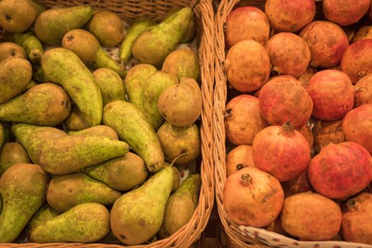 Counter with ripe pomegranates and pears in supermarket 