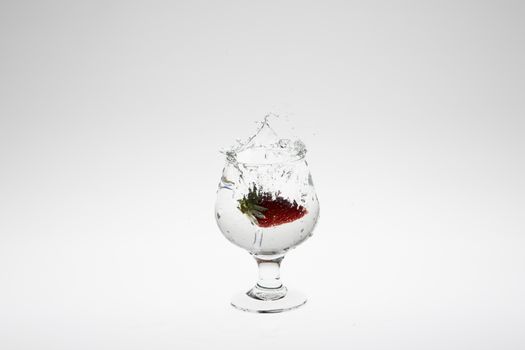 Close-up image of strawberry dropped to water on white background