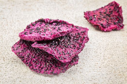 slices of dried red dragon fruit against rustic white painted wood