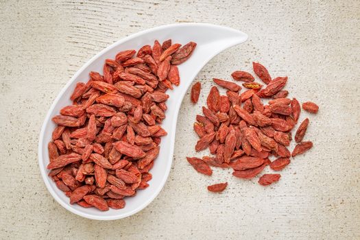 dried goji berries in a teardrop shaped bowl against rustic white painted wood