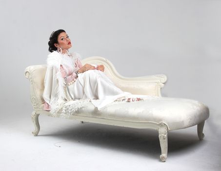 Adult tan woman on sofa with set of pearls